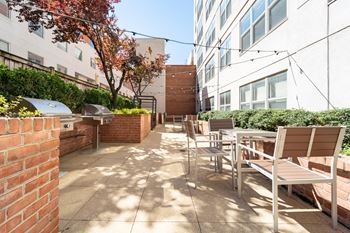 a patio with chairs and tables and a grill on the side of a building at West End Residences, Washington, Washington